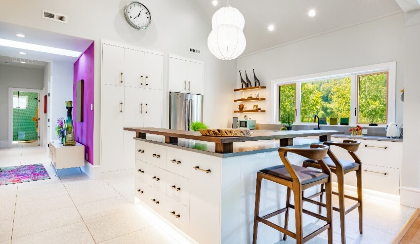 Kitchen with white laminate cabinets, floating shelves, and large island with elevated wood counters