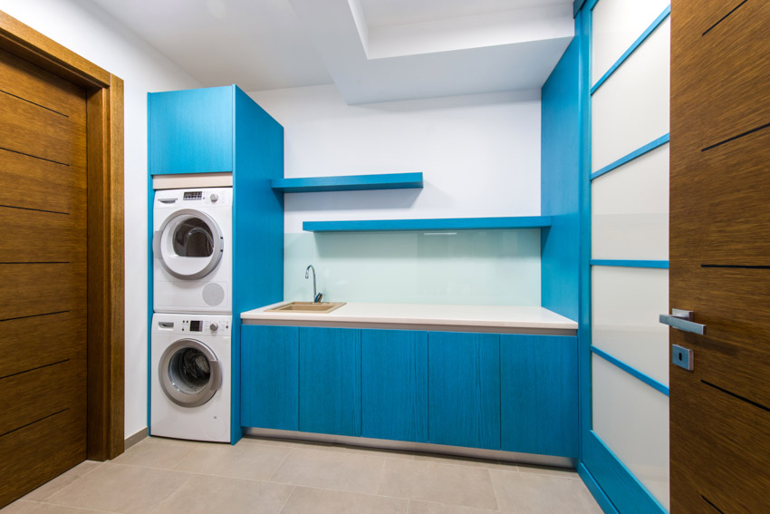 Laundry room with backsplash, blue cabinets, and laundry machines