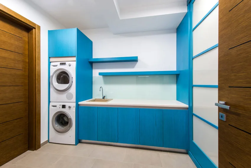 Laundry with backsplash, blue cabinets, and laundry machines