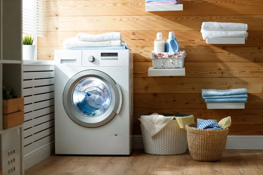 Laundry room with dryer, wood wall, and floors