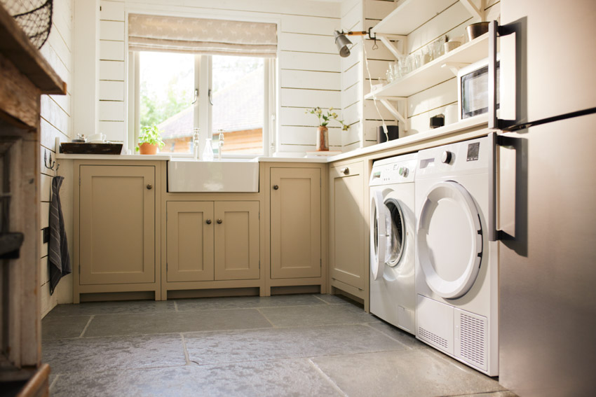 Laundry room with farmhouse style backsplash, cabinets, tile floors, and windows