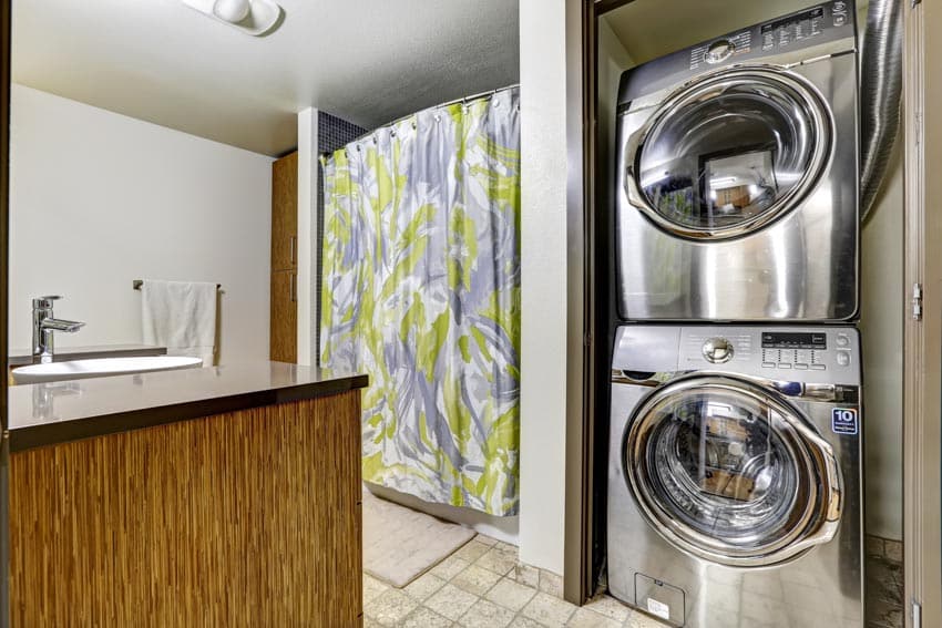 Laundry room with silver stackable washer dryer, sink, and faucet