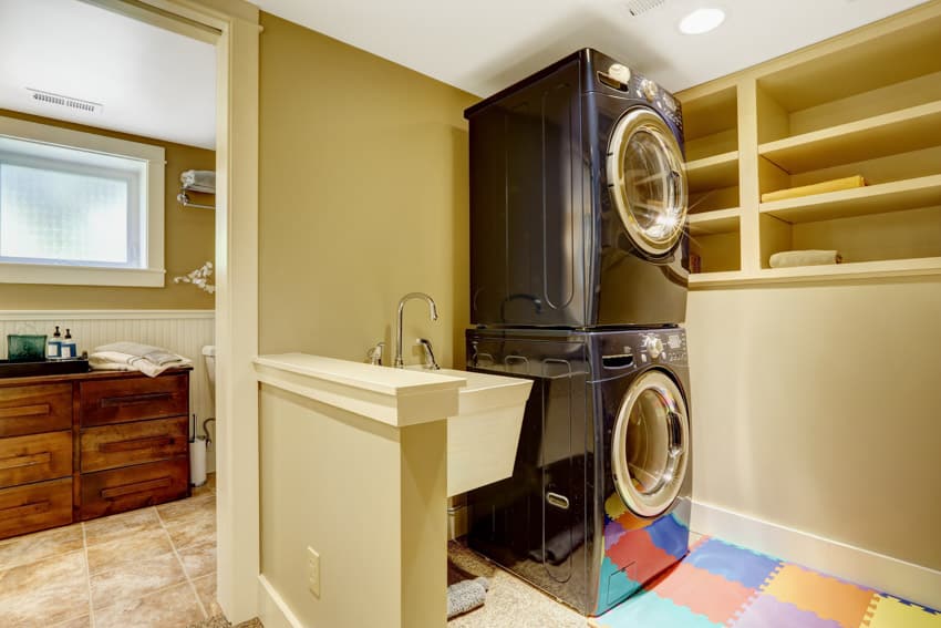 Laundry room with stackable washer dryer, sink, open shelves, and faucet