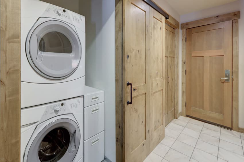 Laundry room with stackable washer dryer, wood doors, and tile floors