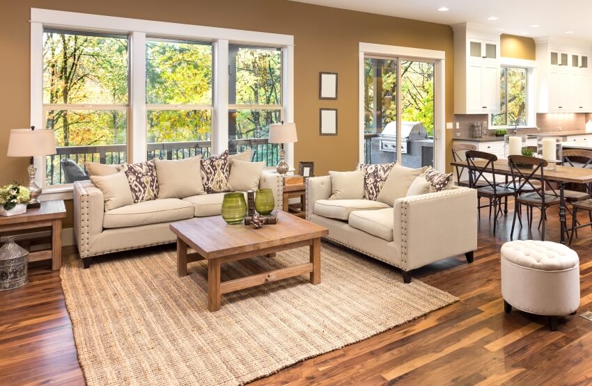 Living room interior with hardwood floors, cream sofa, wood tables, and view of kitchen