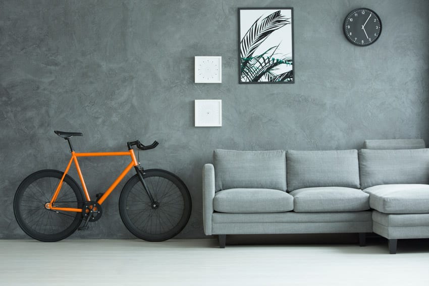 Couch and grey wall, wall art pieces and clock with orange bike