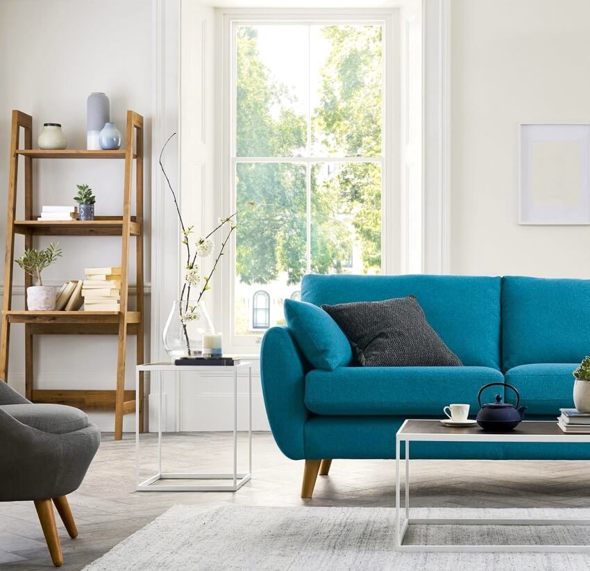 Living room with blue modern sofa, square end table, wooden shelves, and window