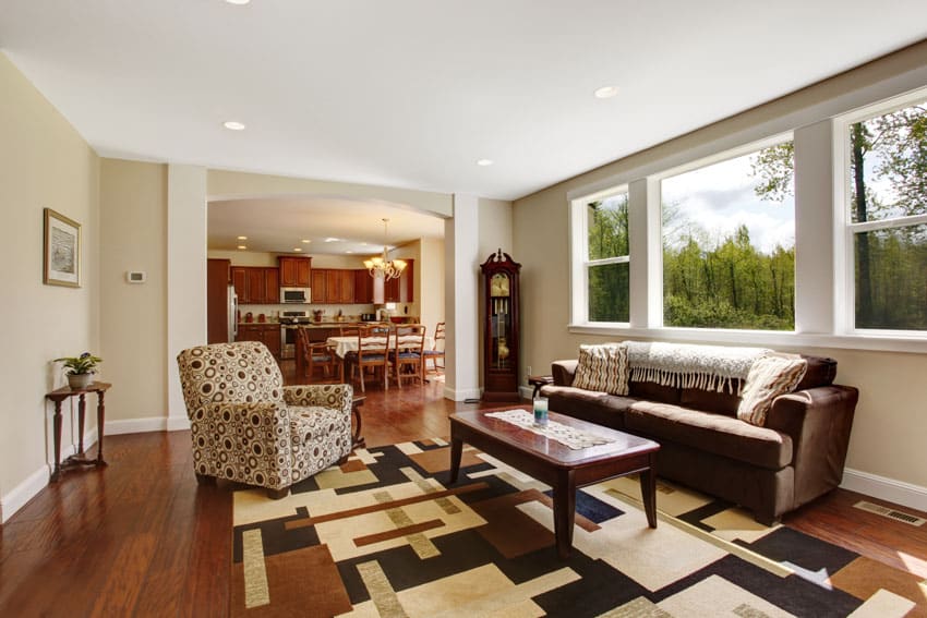 A grandmother clock by the window, a graphic rug and wooden center table