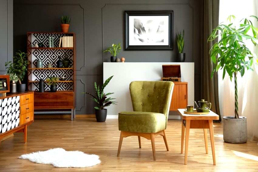 Living room with green armchair, retro cupboards, fresh plants, white rug, and end table with tea set