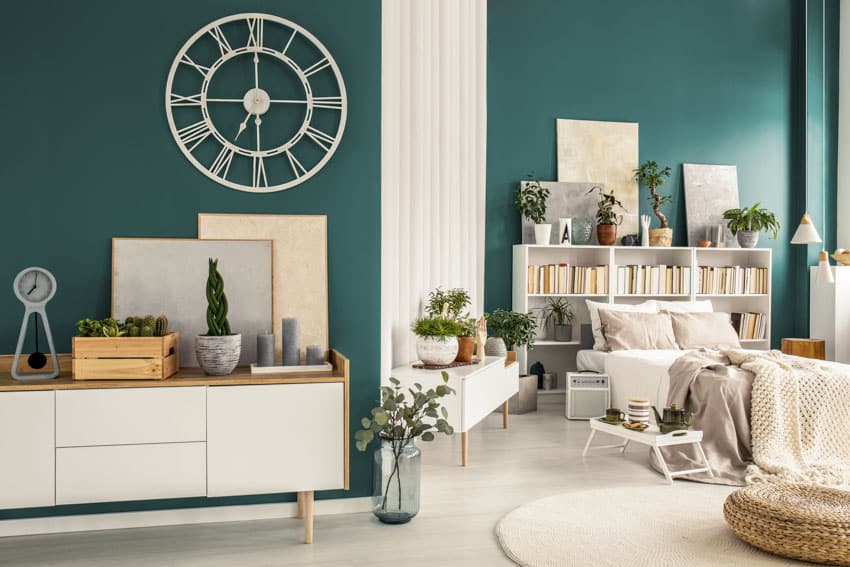 Green wall, white dresser, clock, bookshelf, and console table