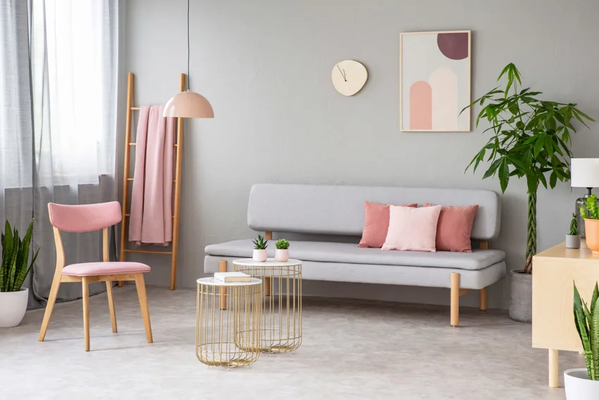 Pink chair, couch, hanging light, gray wall, and window curtains
