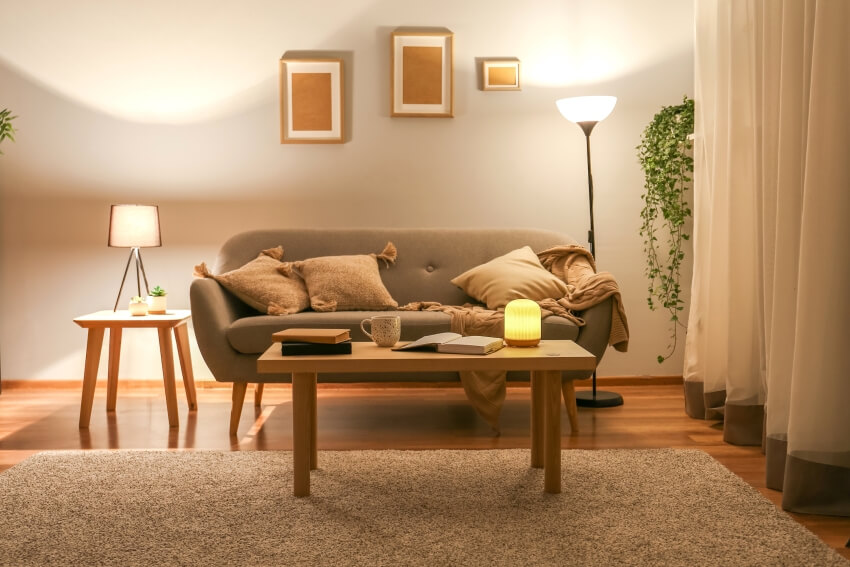 Living room with wood furniture, grey sofa, carpet, wall posters, and mood lighting