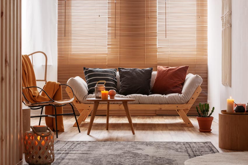 Living space with futon couch, pillows, shutters, chair, and floor rug