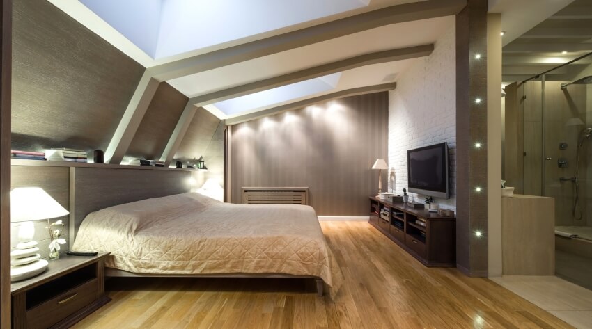 Loft bedroom with brick wall, skylight windows, and neutral-colored mood lighting