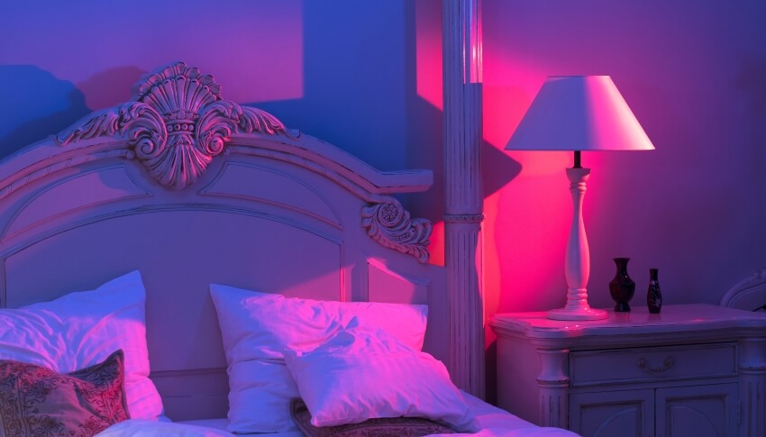 Luxurious bedroom with royal bed, pink and blue light with stylish night lamp at the wooden table