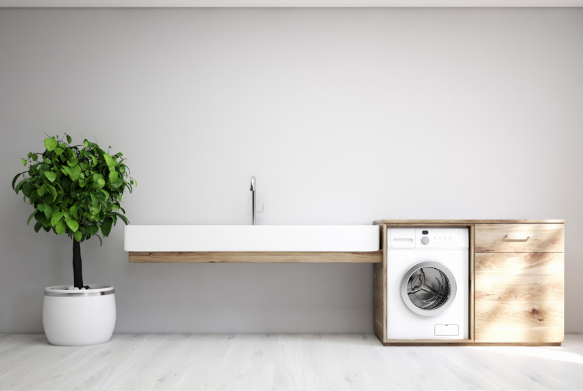 Minimalist kitchen with floating countertop, washing machine, and indoor plant
