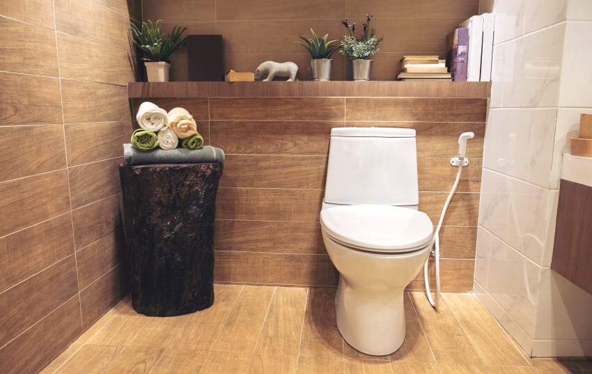 Modern bathroom with wood tile wall and floor and built in shelf with books, plants, and decors