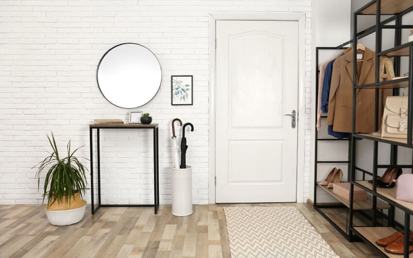Modern entryway with runner rug, mirror on brick wall, and metal framed storage unit