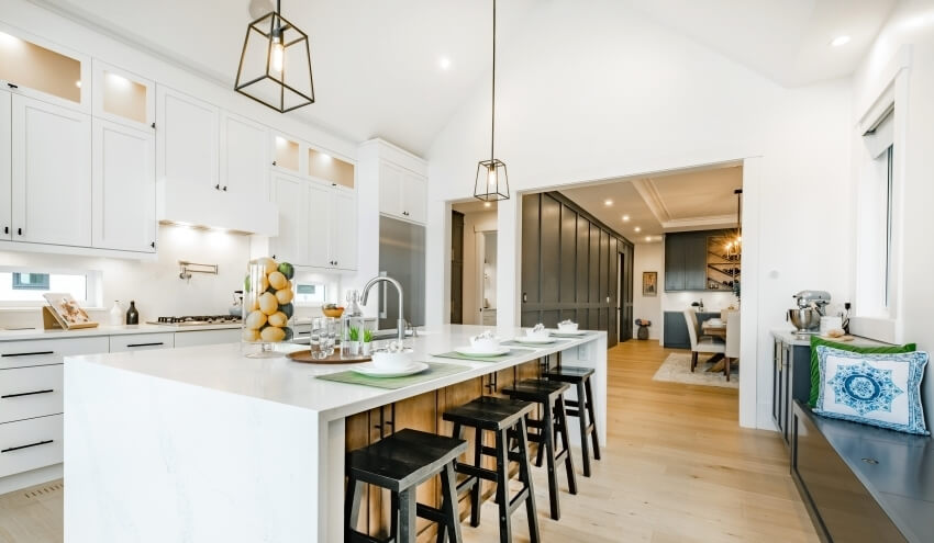 Modern farmhouse kitchen with waterfall island, pendant lights, and white cabinets with black hardware