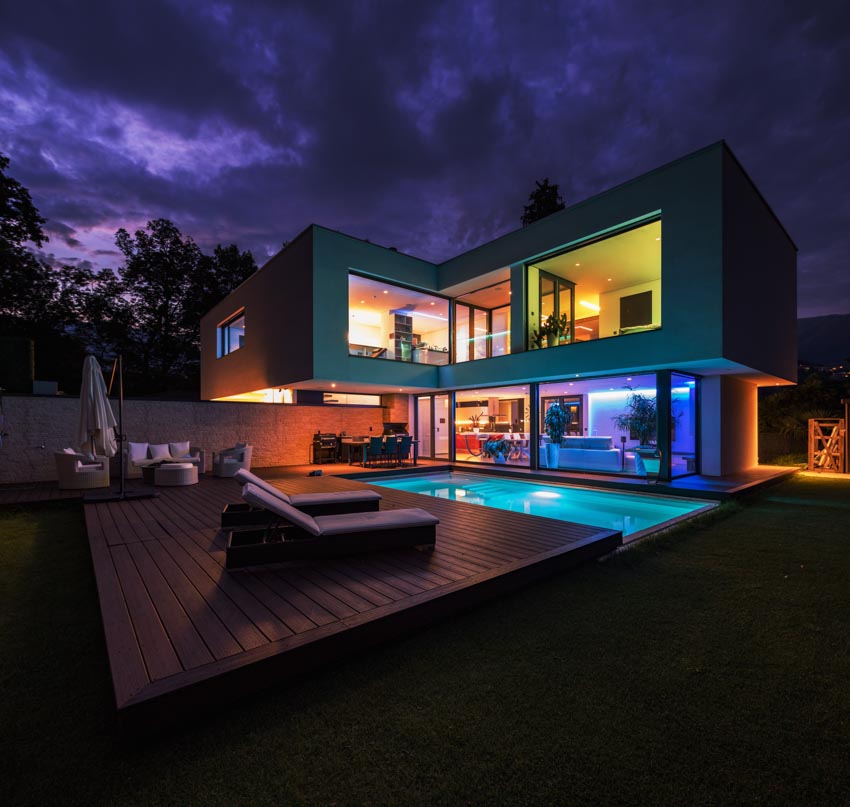 Modern house with colorful lights, deck pool, and picture windows