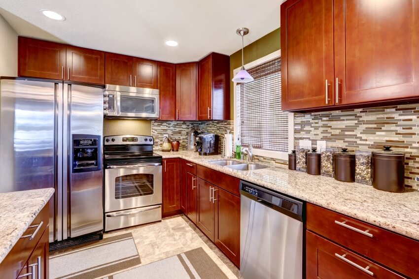 Modern kitchen interior with bright wooden cabinets, mosaic backsplash, and granite countertops