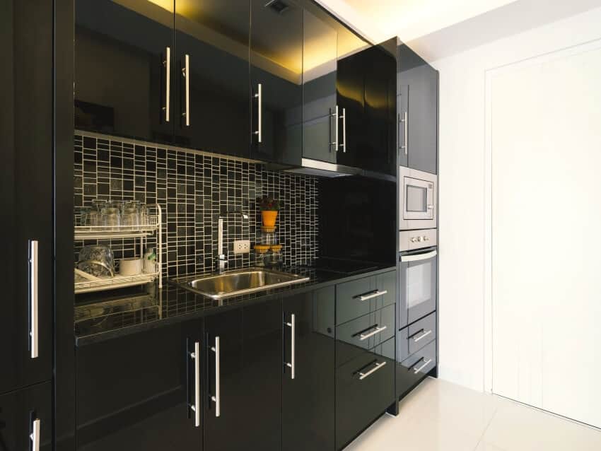 Modern kitchen interior with high gloss black cabinets and tile backsplash