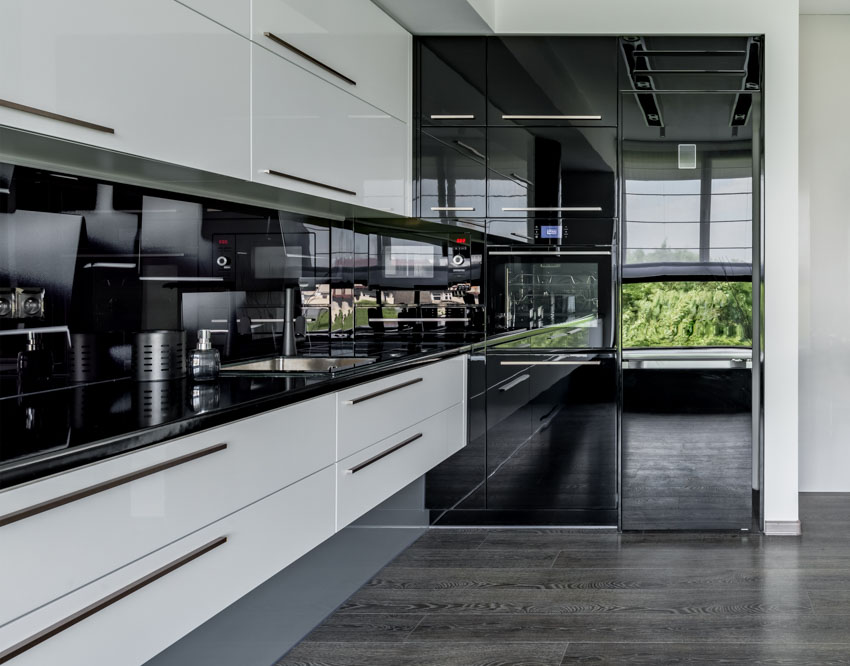Modern kitchen with floating cabinets, countertops, black backsplash, and wood floor