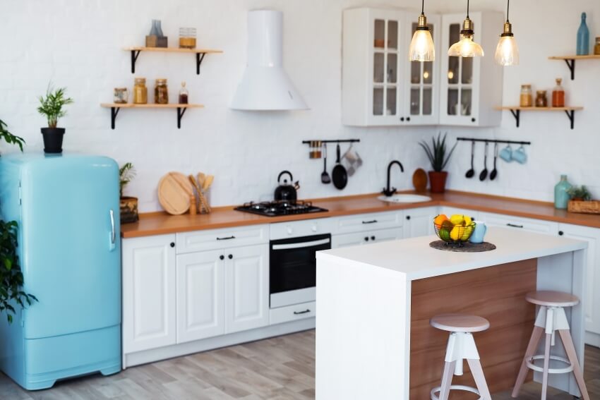 Modern kitchen with floating shelves, sky blue fridge, white cabinets, and small white island