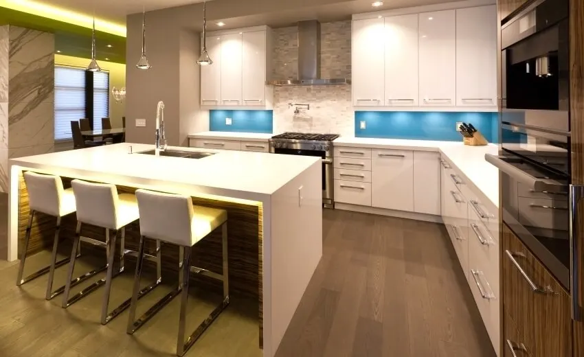 Modern kitchen with glossy cabinets, waterfall island, light blue backsplash, and pendant lights