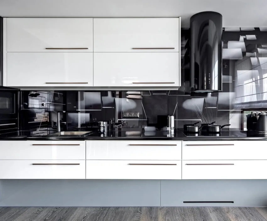 Modern kitchen with high gloss white cabinets, and black backsplash, countertops and cylinder range hood