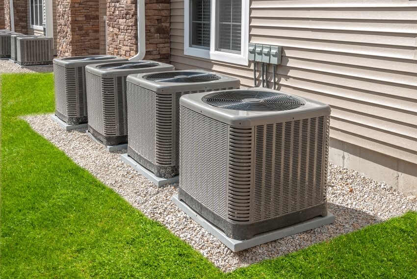 Modern natural gas air conditioning and heating units outside of a house with shiplap siding