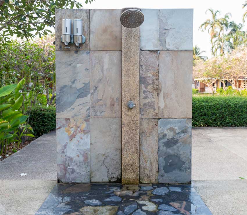Modern outdoor shower with stone tiled wall, and showerhead