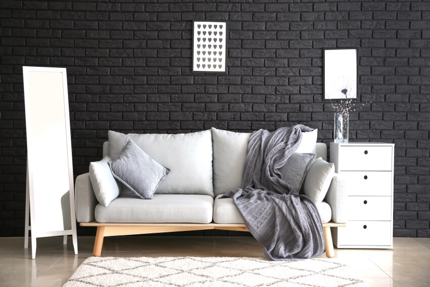 Modern room with mirror and stylish sofa near black wall