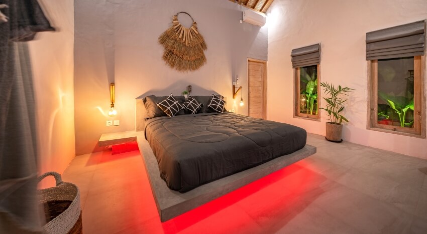Modern stone pine bed with red LED lighting, wall lamps, and concrete walls and floor