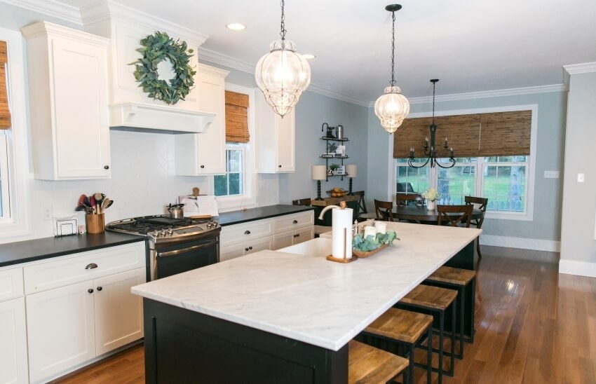 Modern white kitchen with cabinets, a mix of granite and quartz countertops, and pendant lights