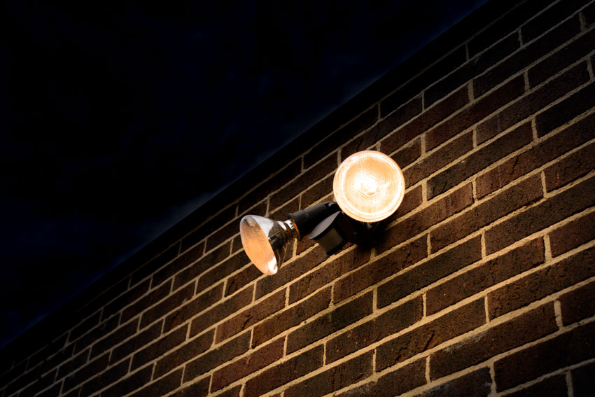 Flood-type lighting fixture on black brick-style wall