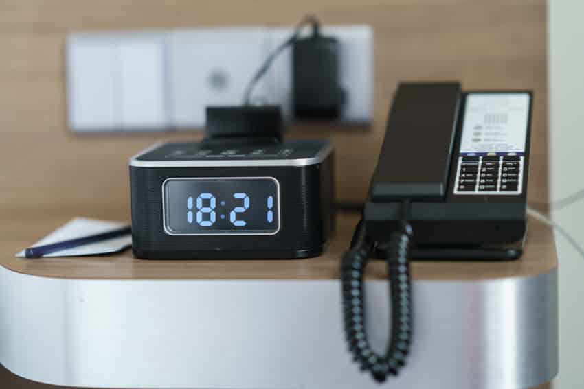 Black clock and telephone on table