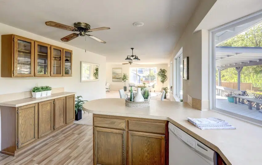 Open kitchen with wood cabinets ceiling fan, panel floor, and cream-colored countertops