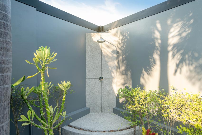 Outdoor area in a corner with showerhead, shower floor, and plants