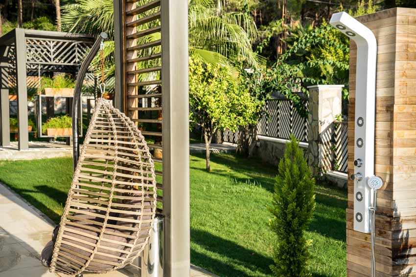 Trendy showerhead on wooden pillar with view of a swing seat