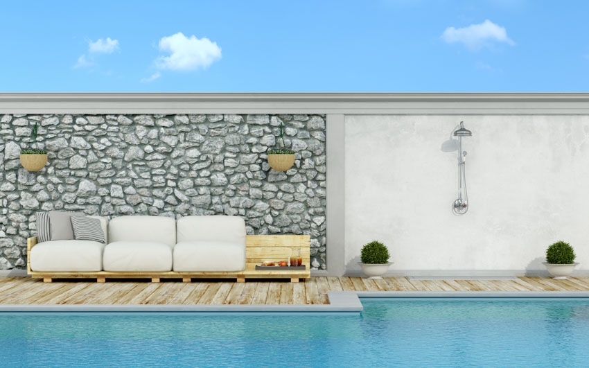 Outdoor pool with couch, stone accent wall, and shower area