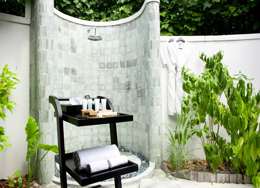 Outdoor shower enclosure with tile wall, and plants