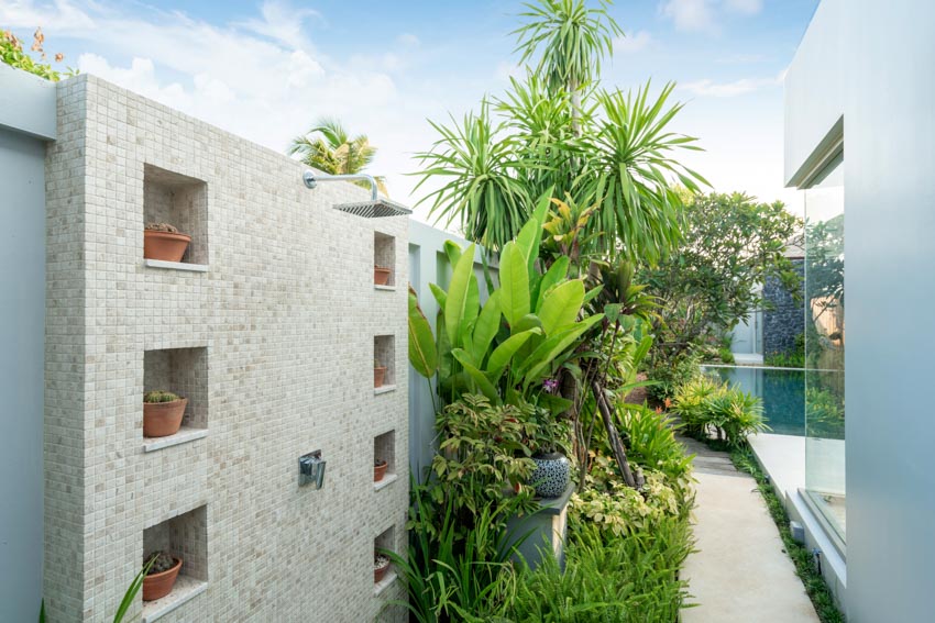 Discreet placement of shower by adding it to the wall with recessed spaces for potted plants