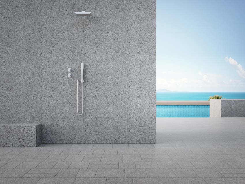 Outdoor shower with tile floor, dual showerhead, and concrete wall