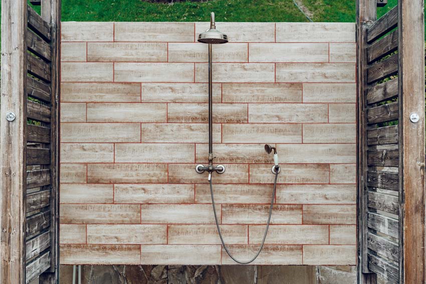Shower with tiled wall design and dark planks on each sides with rainshower head