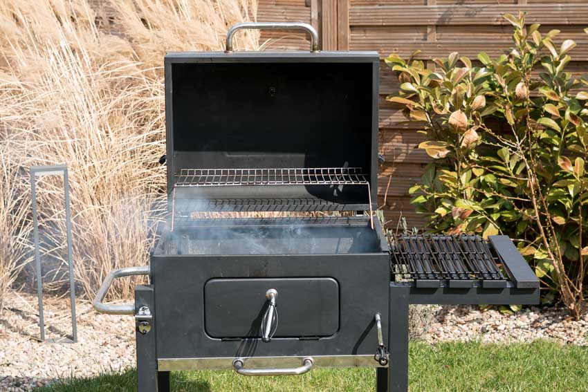 Pros and cons of pellet grills with one emitting smoke in a backyard area