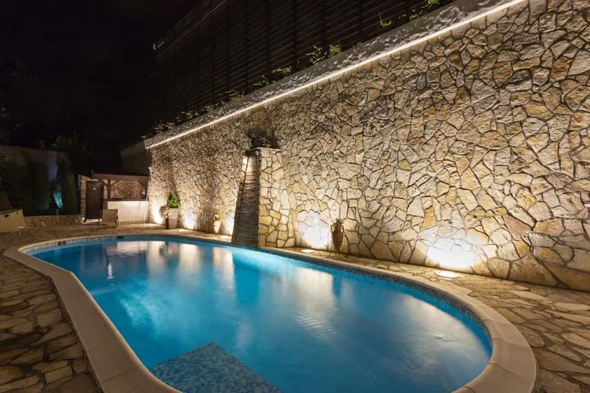 Pool area with uplighting, and stone wall