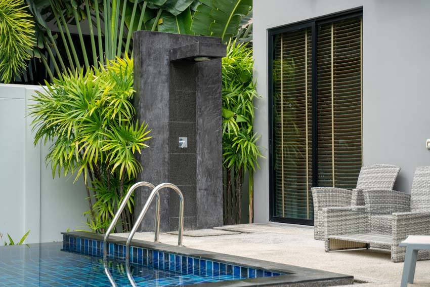 Black wall with shower beside the pool