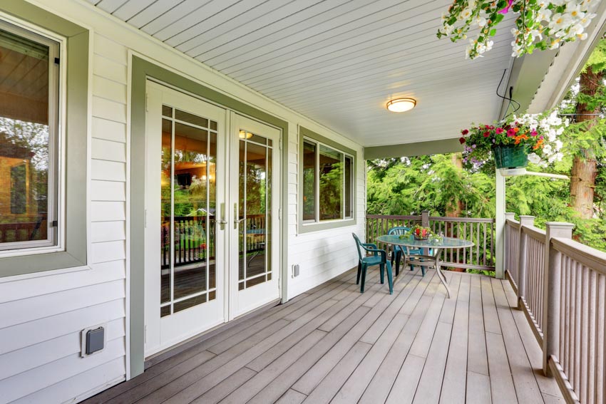 Porch area with front door, green and white painted walls, windows, siding, ceiling light, outdoor furniture