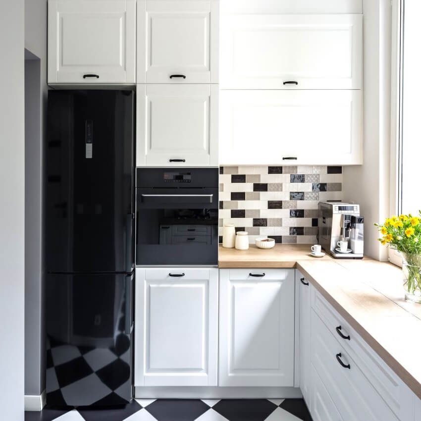 Small kitchen with chess flooring, wood countertop, and white cabinets with black hardware